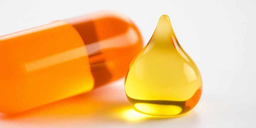 Vibrant orange vitamin A capsule beside shimmering omega-3 fish oil.